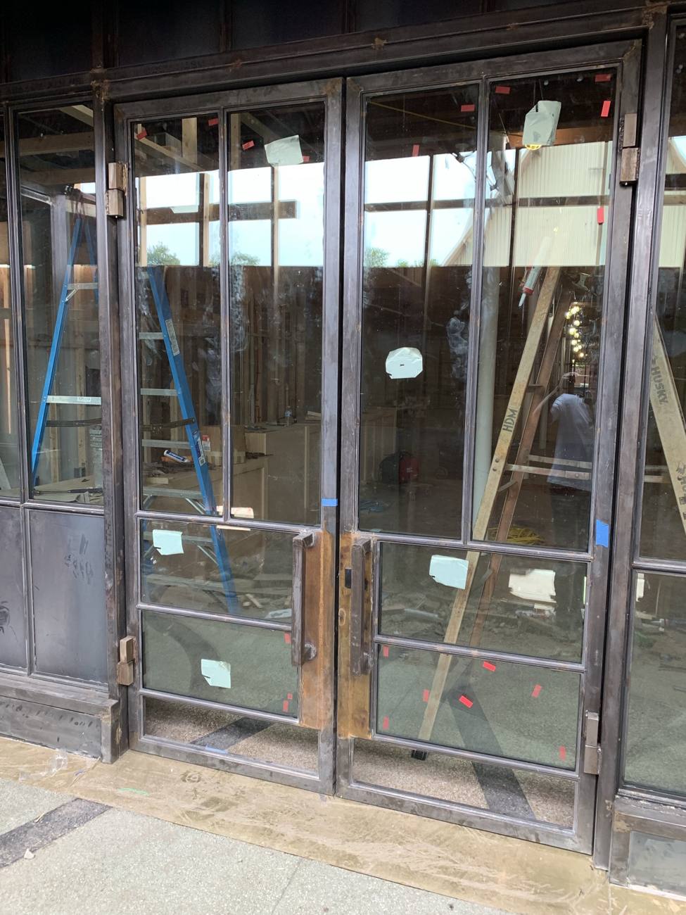 Steel double doors set in a storefront, glazed and labeled before cleaning